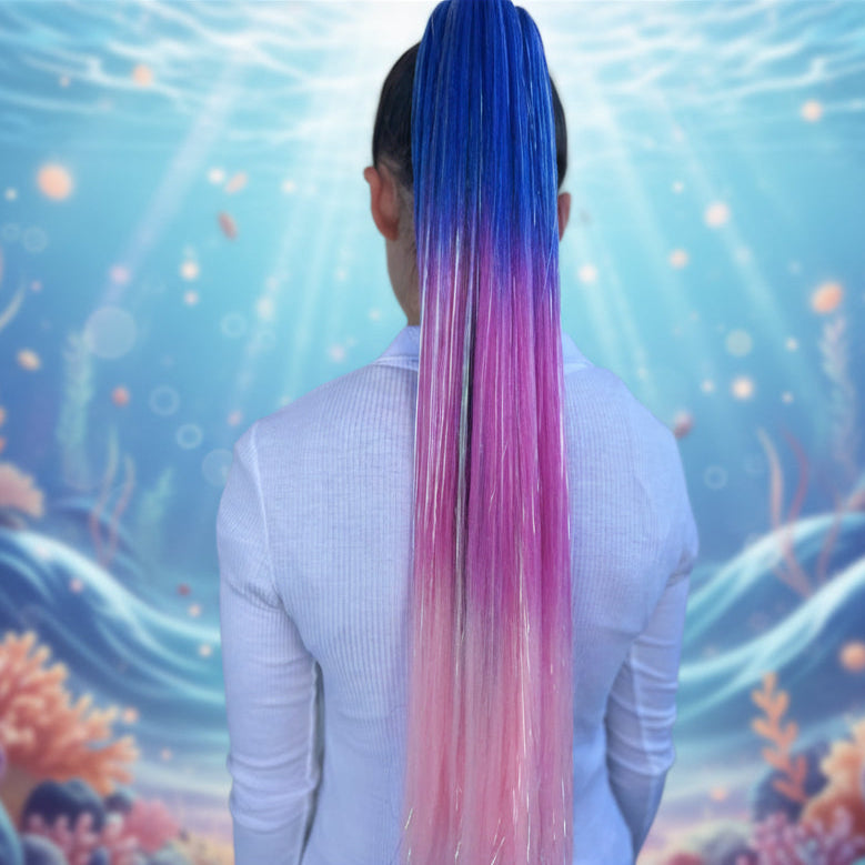 Person with blue to pink ombre hair against a plain background