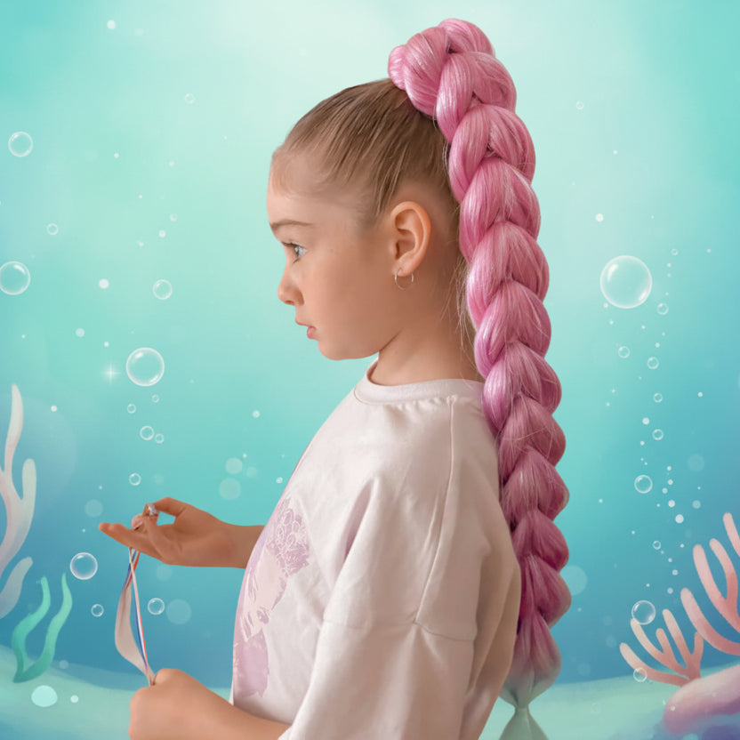 Child with pink dragon braid hair against a mermaid-themed background