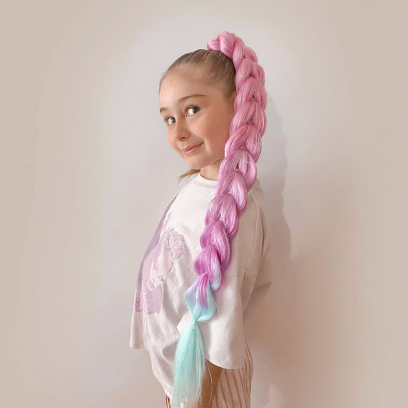 Young girl with a long, colorful dragon  braid standing against a plain background