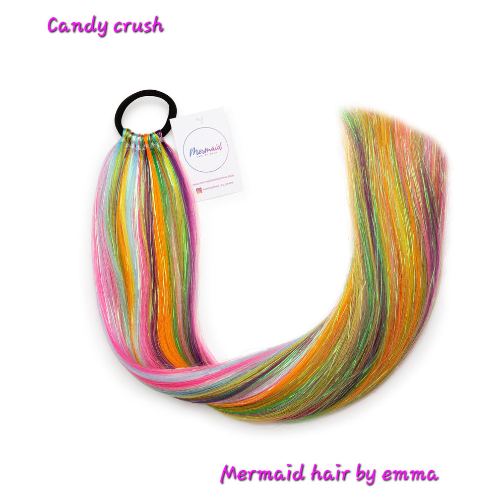 A set of multicolored mermaid hair extensions with an elastic band, labeled 'Candy crush' by 'Mermaid hair by emma'.