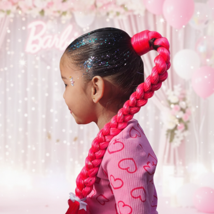Child with pink braided hair and sparkling hair accessories against a soft, blurred background
