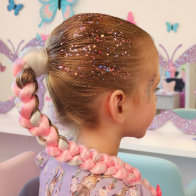 Child with braided hair and colorful decorations in a room with butterfly decorations.