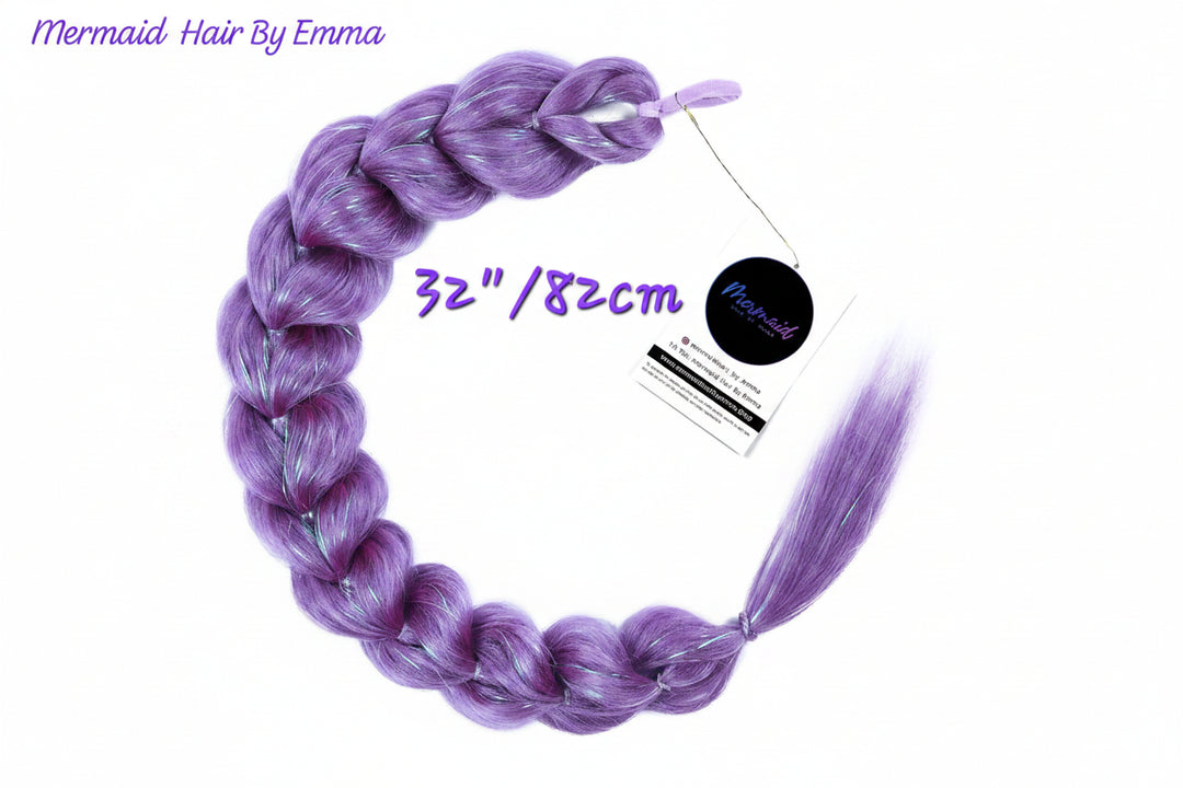 A single long braided synthetic hair extension in a lavender-purple color, displayed on a white background with a product tag and text overlays indicating 'Mermaid Hair By Emma' and '32"/82cm'.