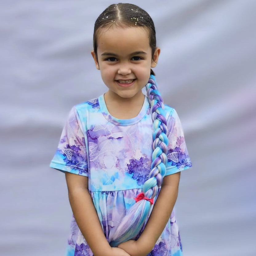 Young girl wearing a colorful dress with a floral pattern against a gray background