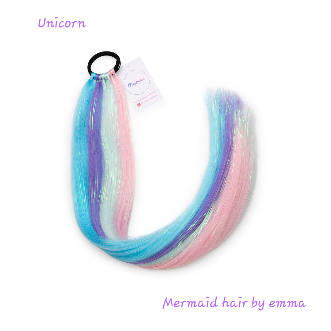A set of multicolored mermaid hair extensions with an elastic band, labeled 'Unicorn' and 'Mermaid hair by emma'.