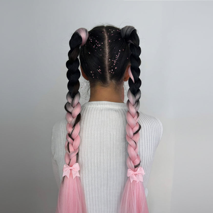 A child with mermaid-style hair extensions in black tied with pink ribbons, with the extension visible in a close-up view.